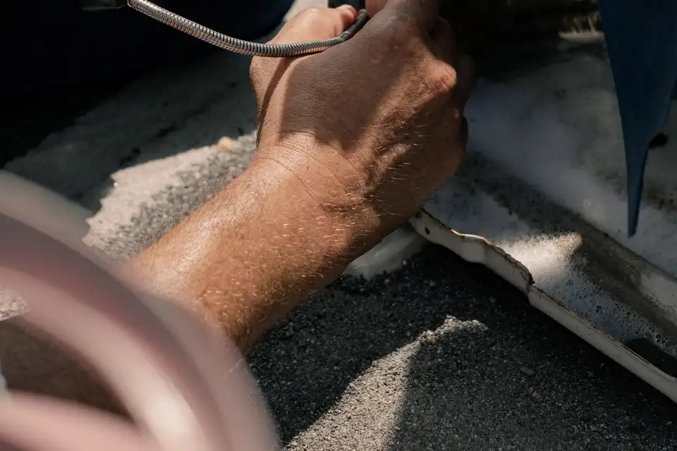 Technician's hands holding a meter lead against an outdoor cooling unit